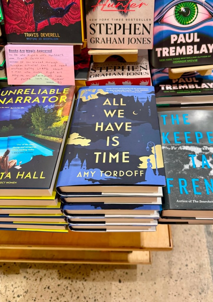 A stack of All We Have is Time on a table with other books for sale
